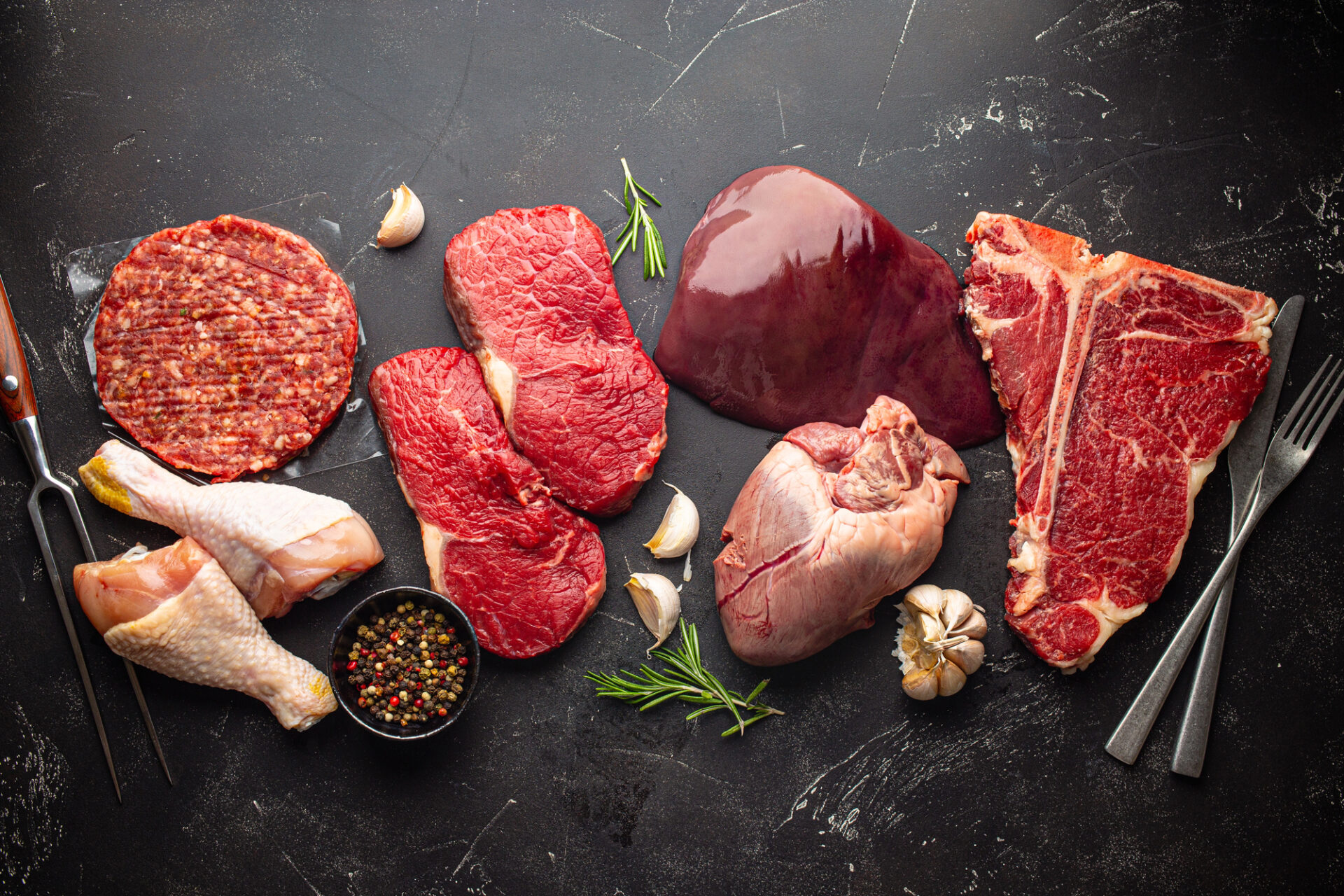 Da sinistra a destra: cosce di pollo, hamburger o tartare di bovino, fettine di bovino, fegato, cuore e T-bone; concept: carne rossa, dieta carnivora