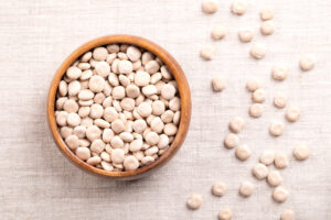 Lupini secchi in una ciotola di legno, con lupini sparsi; concept: legumi