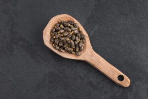 Semi di ricino su una paletta di legno, Ricinus communis; concept: ricina