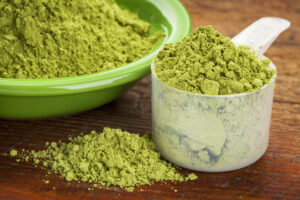 Polvere di moringa in un misurino e in una ciotola verde; concept: integratori