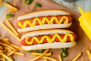 Due hot dog con senape circondati da patatine