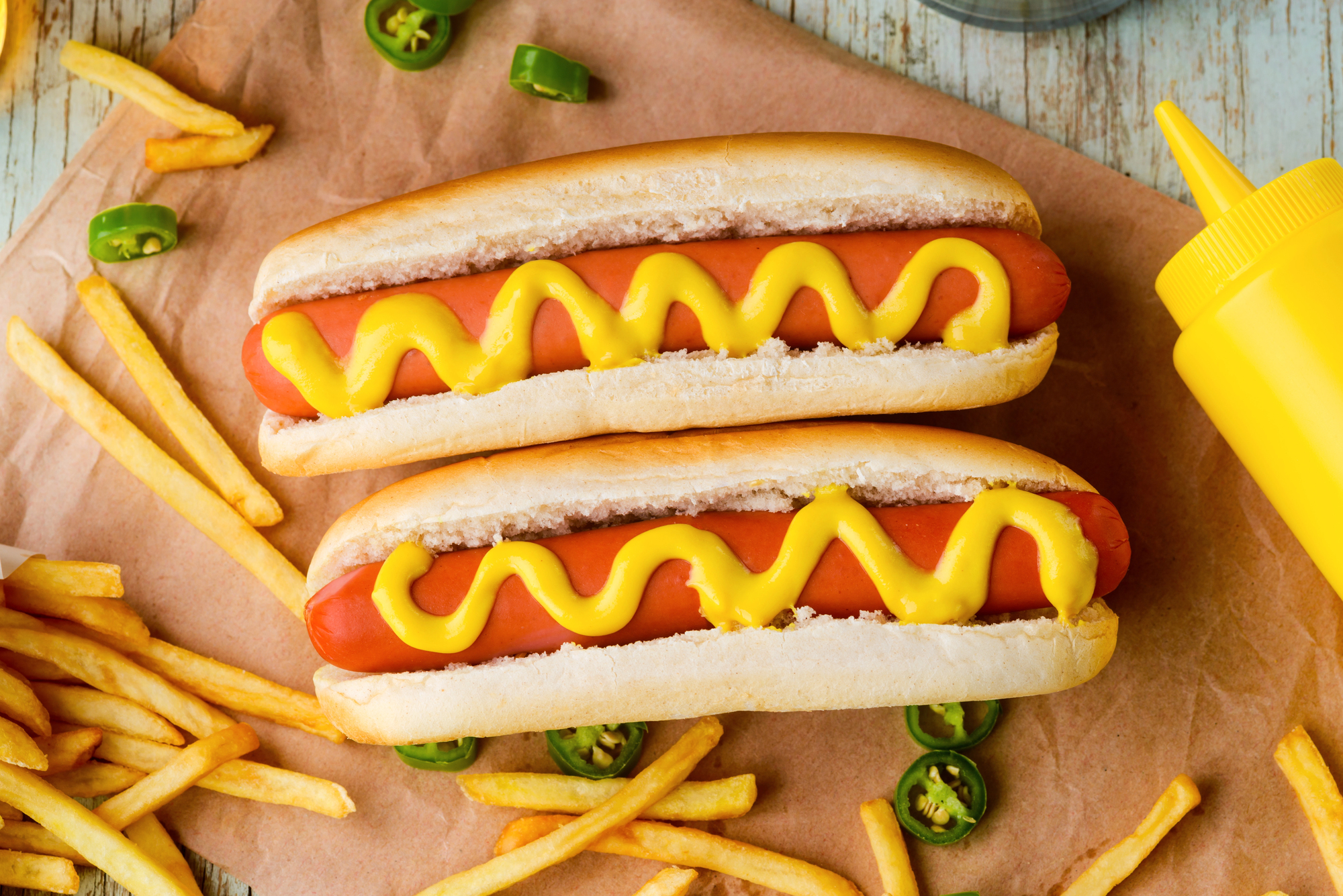 Due hot dog con senape circondati da patatine