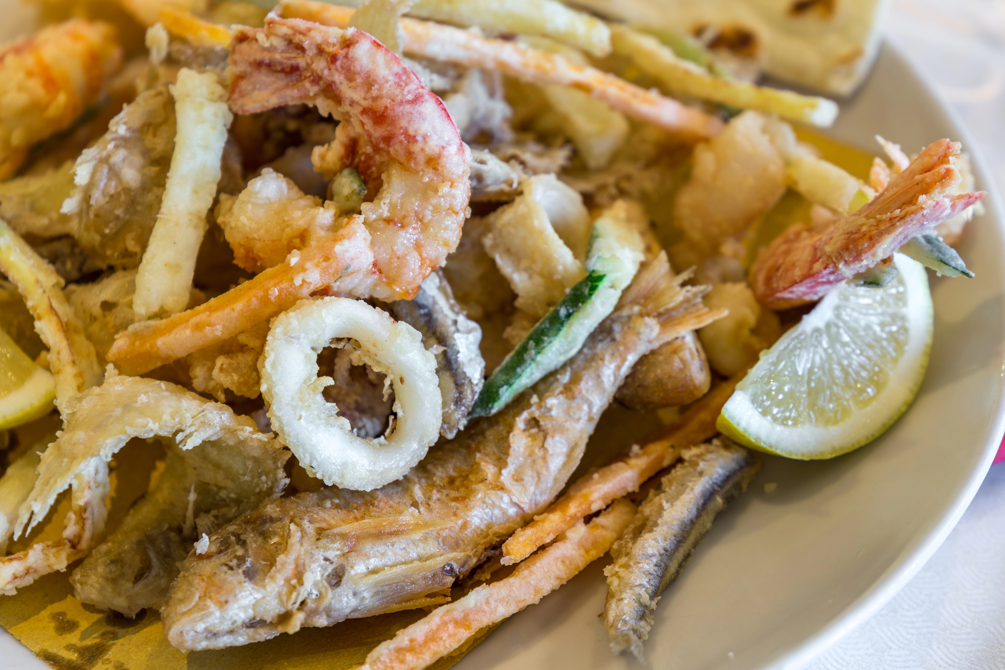 Un piatto di fritto misto di pesce con gamberi. calamari o totani, pesce azzurro e verdure