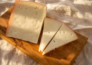 Fette di formaggio stagionato con i buchi su un tagliere di legno