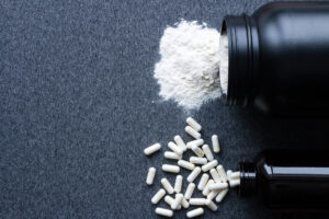 Un barattolo rovesciato di proteine o creatina, accanto a un barattolo rovesciato di integratori alimentari; concept: palestra, bodybuilding