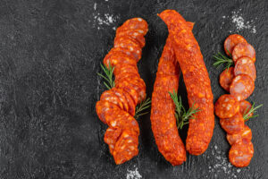 Quattro salami o salsicce piccanti, due intere al centro e due a fette; concept: salame, salumi