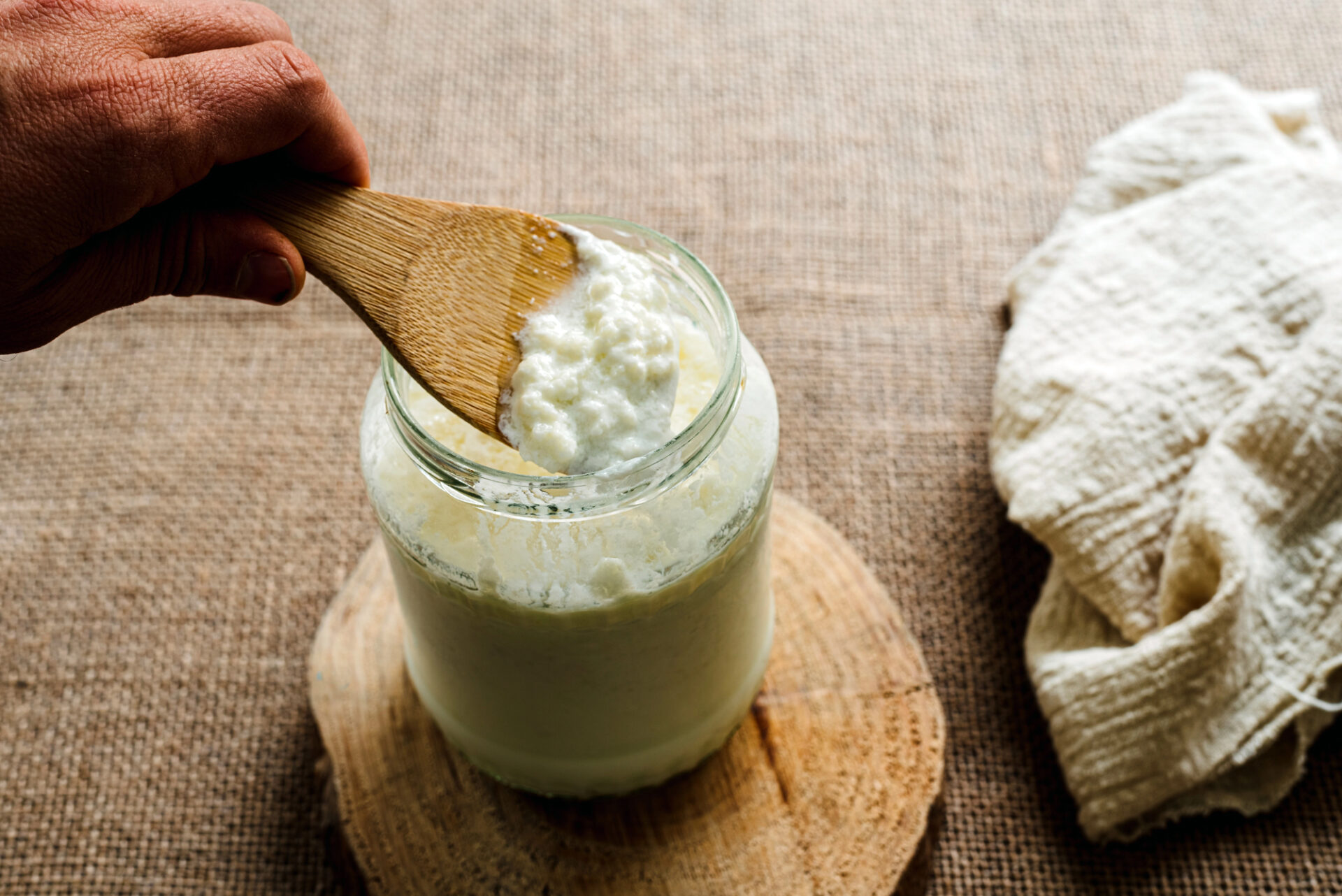 Un uomo toglie o mette granuli di kefir in un vaso di latte o kefir fatto in casa