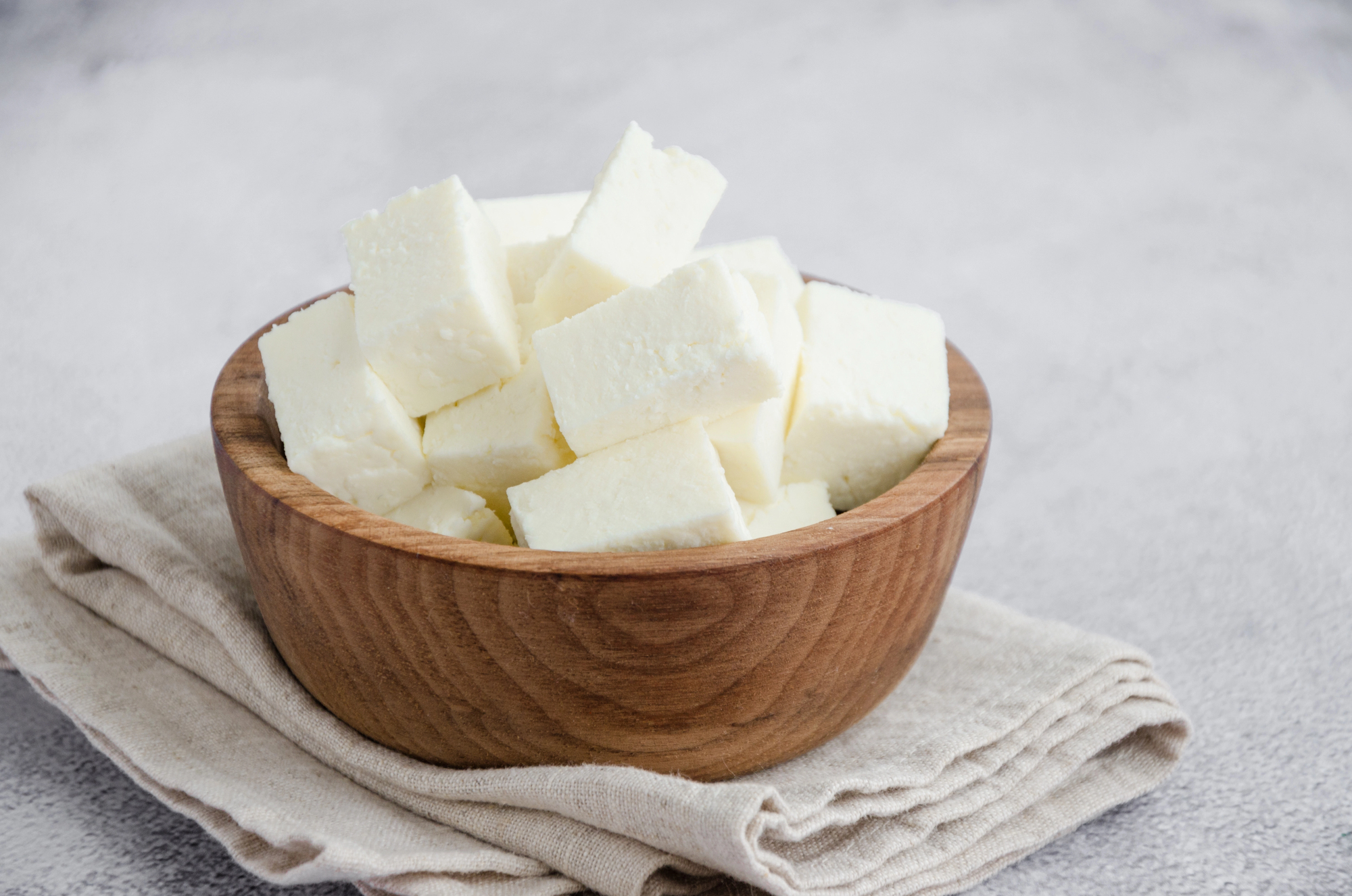 Cubi di paneer in una ciotola di legno, formaggio tipico di India e Pakistan
