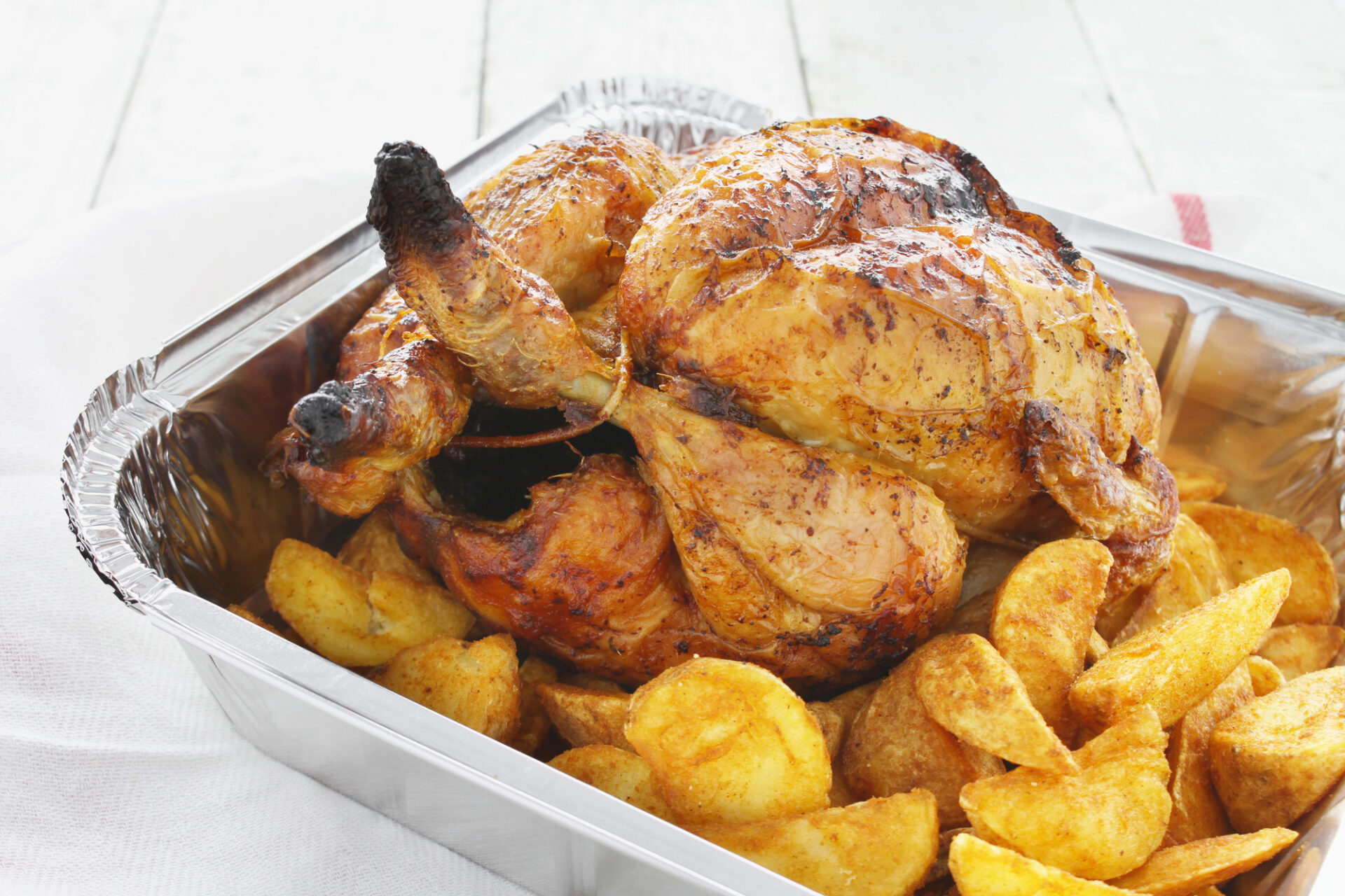 Una vaschetta di pollo arrosto con patate; concept: cibo da asporto, food delivery