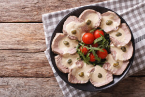 Un piatto di vitello tonnato con pomodorini e rucola
